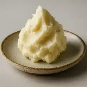 Homemade shea butter cream in a glass jar surrounded by natural skincare ingredients, symbolizing DIY skincare as a radical act of self-care and connection with nature.